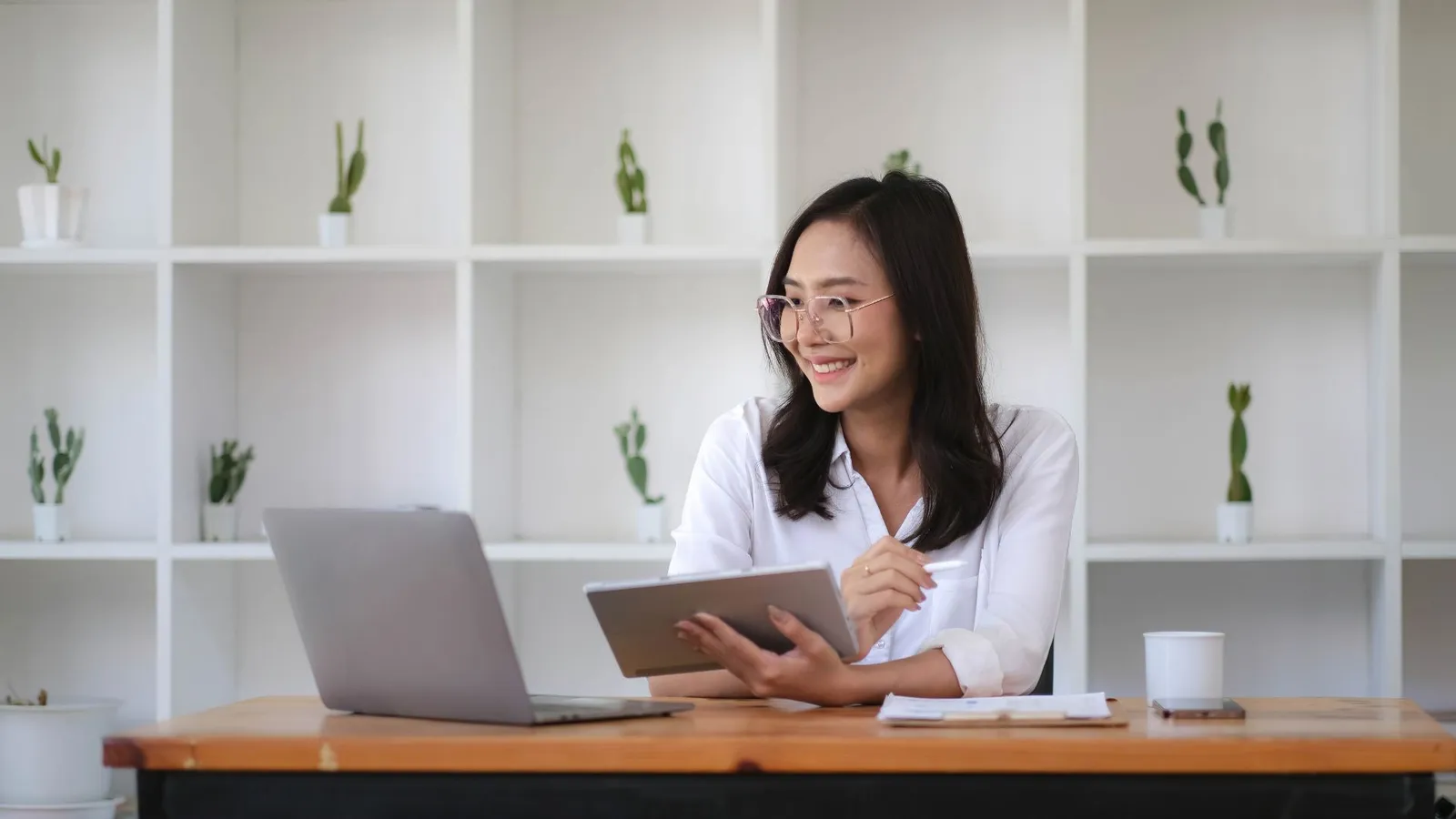 Jeune femme souriante révisant le français sur tablette et ordinateur pour atteindre le niveau B2